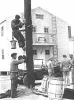 Raymond Speer (on pole) and Joe Hendricks install a fire alarm station at Camp Atterbury