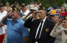 Don Coleman, left, and his father-in-law Sam Hobson join other veterans in saluting the flag during the singing of the National Anthem at Saturday's Memorial Day observance at the Anderson County Veterans Monument.